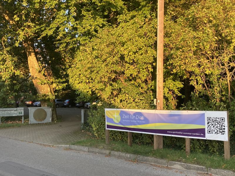 Seit 2024 hat das Banner "Spiritueller Sommer im Norden" vor der Einfahrt zum "Haus der Stille" in Weitenhagen eigens errichtete Pfähle..