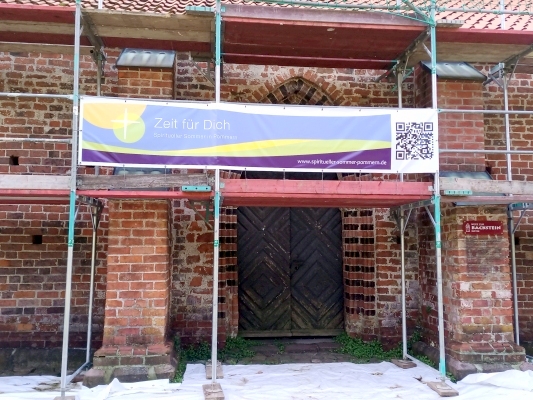 Banner "Spiritueller Sommer" an der Backsteinbasilika St. Jürgen in Starkow.
